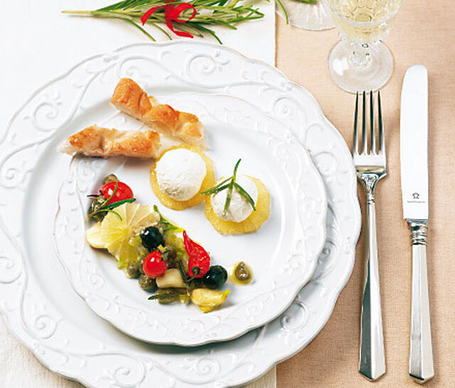 Ein festlicher weißer Teller mit kleinen Happen und einem kleinen Salat belegt