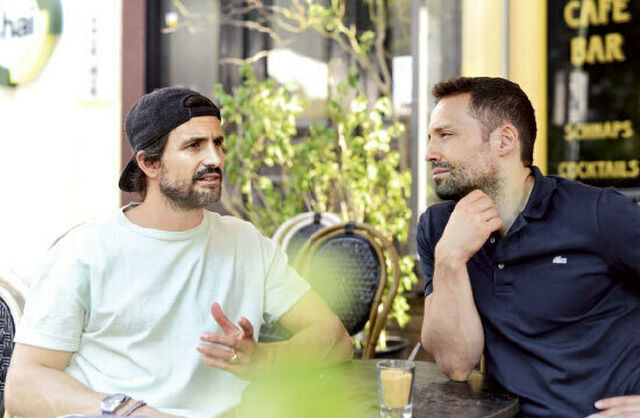 Schauspieler Tom Beck und Schrot & Korn Autor Renato Leo sitzen zusammen in einem Cafe und unterhalten sich.