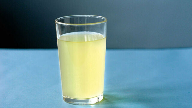 Ein Glas mit Sauerkrautsaft steht auf einem blauen Tisch.