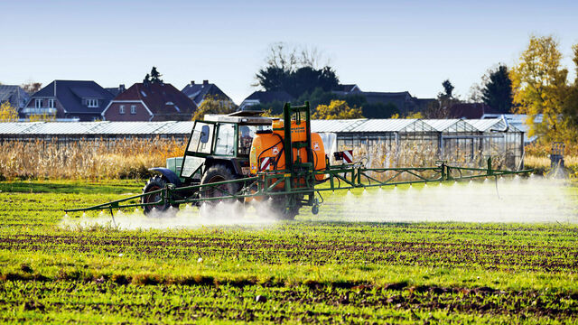 Traktor sprüht Pestizide auf ein Feld