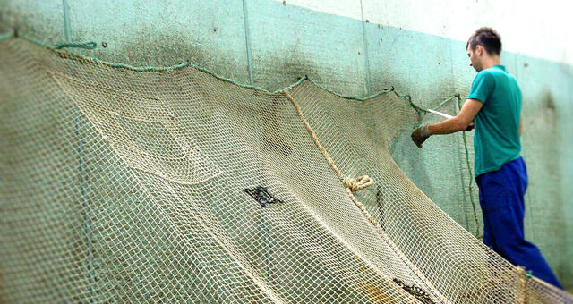 Ein Mann befestigt Fischernetze.