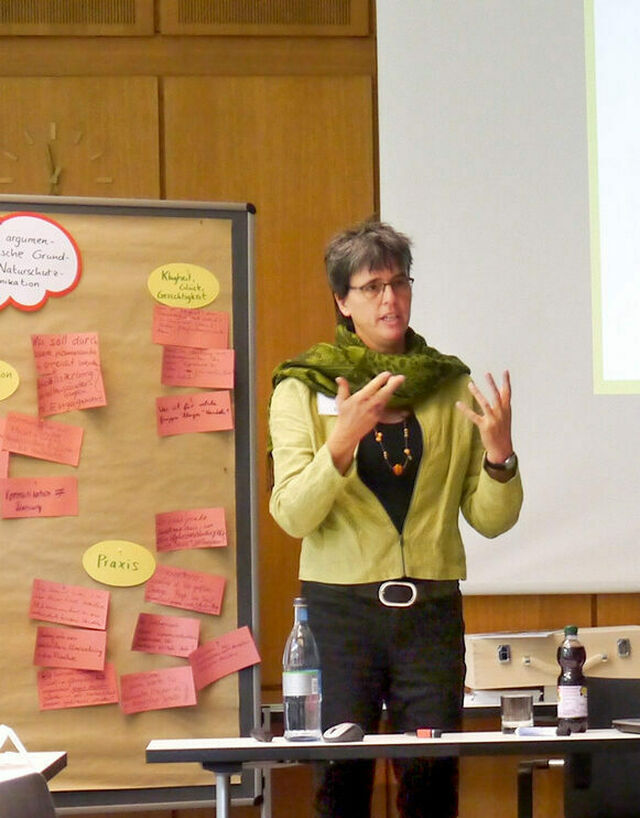 Uta Eser: Frau mit grüner Jacke und schwarzer Hose vor Flip-Chart
