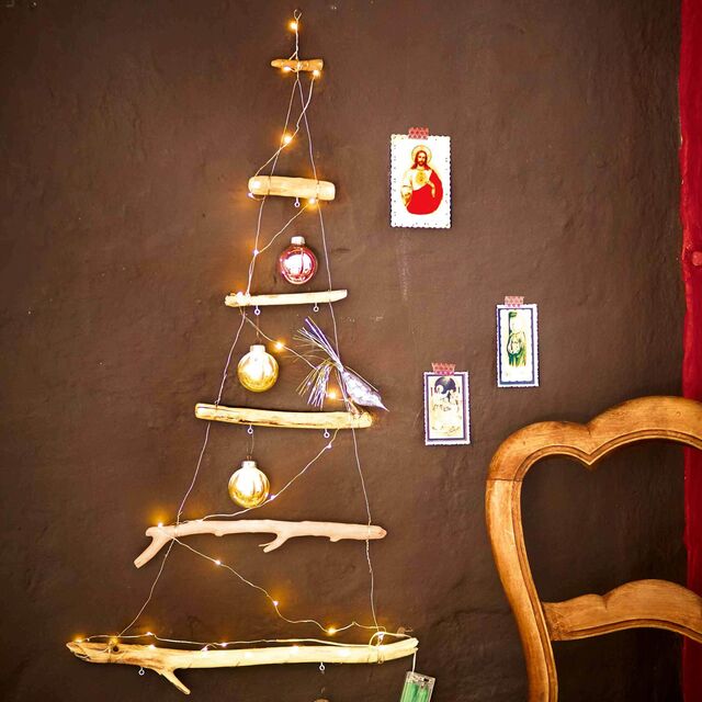 Weihnachtsbaum aus Ästen, geschmückt mit Kugeln und Lichterkette