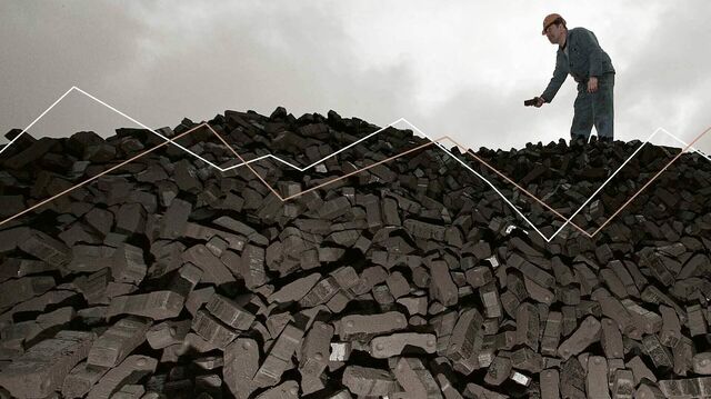 Divestment: Ein Arbeiter steht auf einem riesigen berg an Kohlebriketts