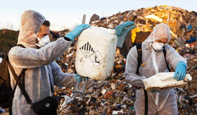Reporter auf einer illegalen Müllhalde hält einen Kanister in der Hand