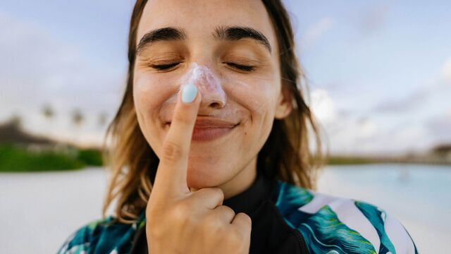 Eine Frau cremt sich die Nase mit Sonnencreme ein