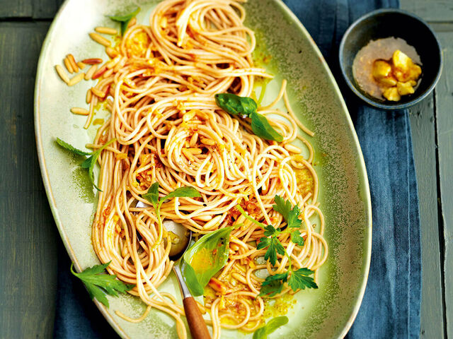 Ein ovaler Teller von oben gefüllt mit Spaghetti, Käutern und Gewürzen.