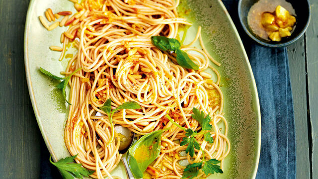 Ein ovaler Teller von oben gefüllt mit Spaghetti, Käutern und Gewürzen.